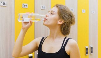 beautiful women drinking water in gym with black exercises outfit