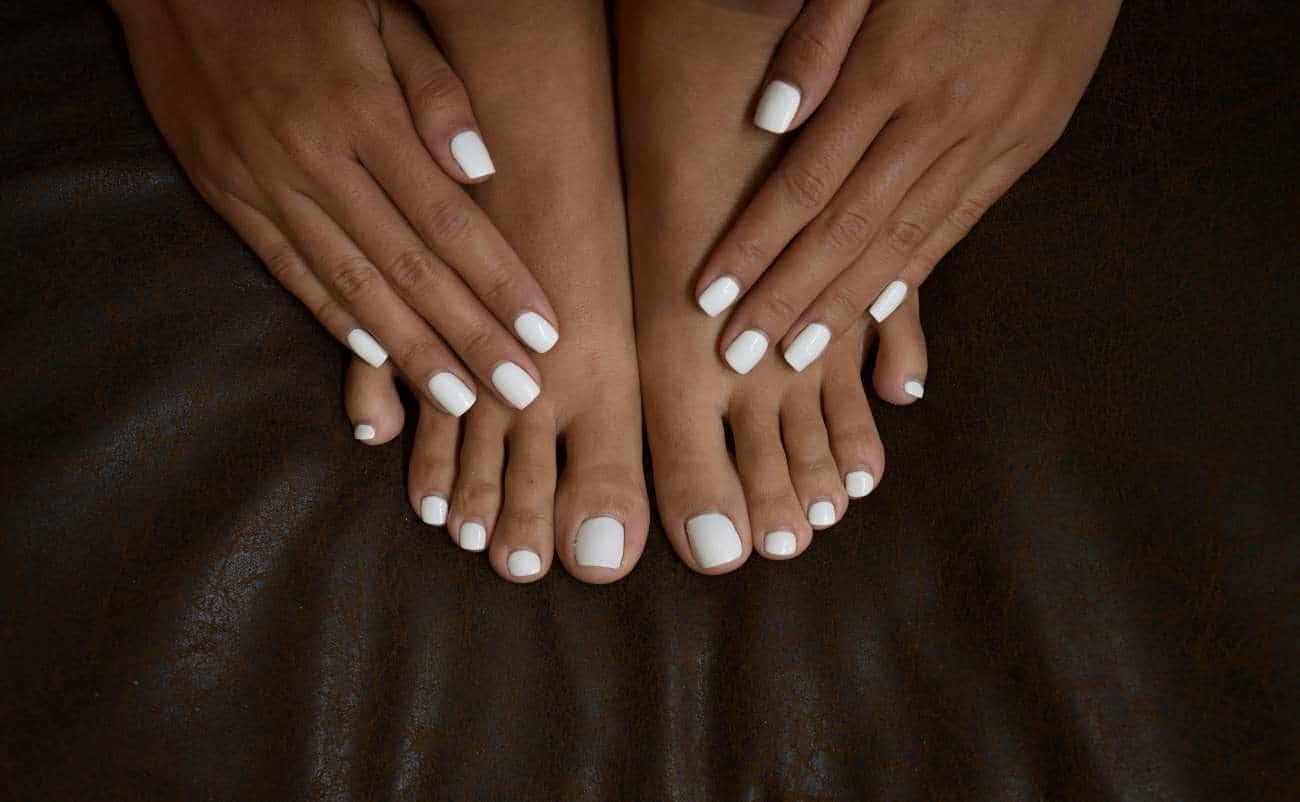 black women doing manicure and pedicure at home in dark background