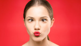 girl making funny face eye in red background