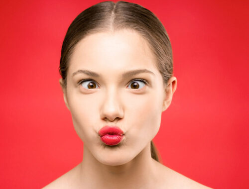 girl making funny face eye in red background