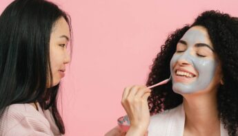 women applying skin care product on face at salon