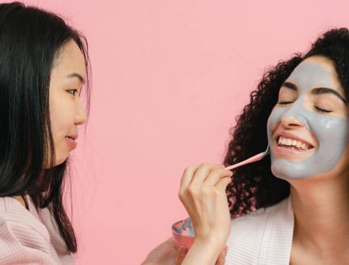 women applying skin care product on face at salon