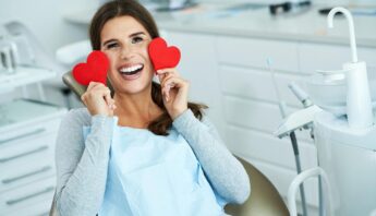 Women smilling and showing her white teeth with two red heart in hand