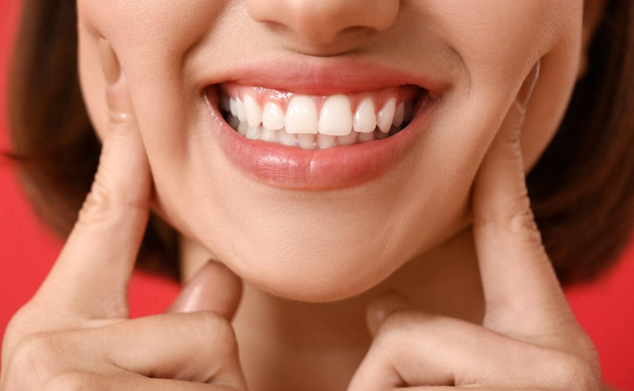 Women smiling and showing her white teeth with two hand