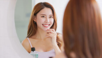 Women smiling and cheking her white teeth in mirror