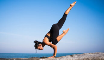 women doing gymnastics on rock beside blue ocean in black costume