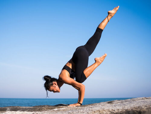 women doing gymnastics on rock beside blue ocean in black costume