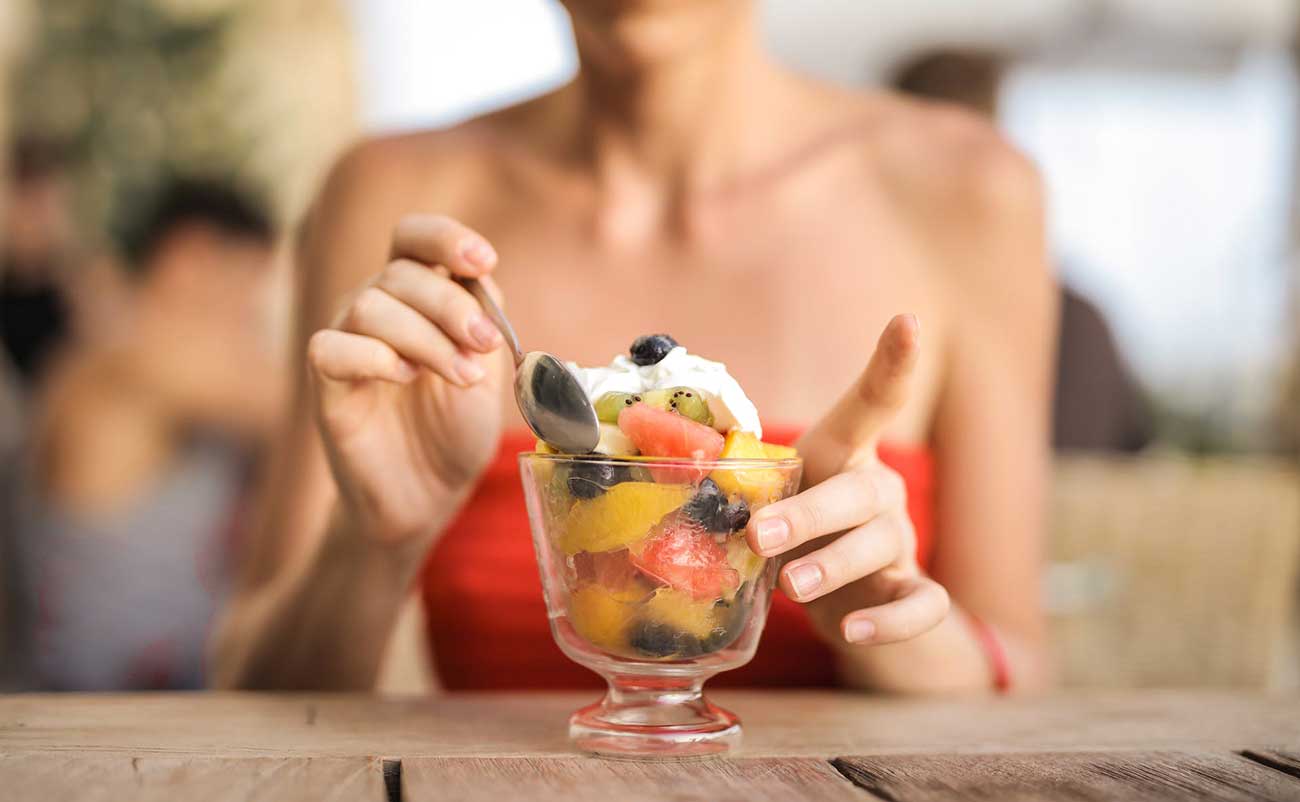 women mixing fruits withicecream in glass