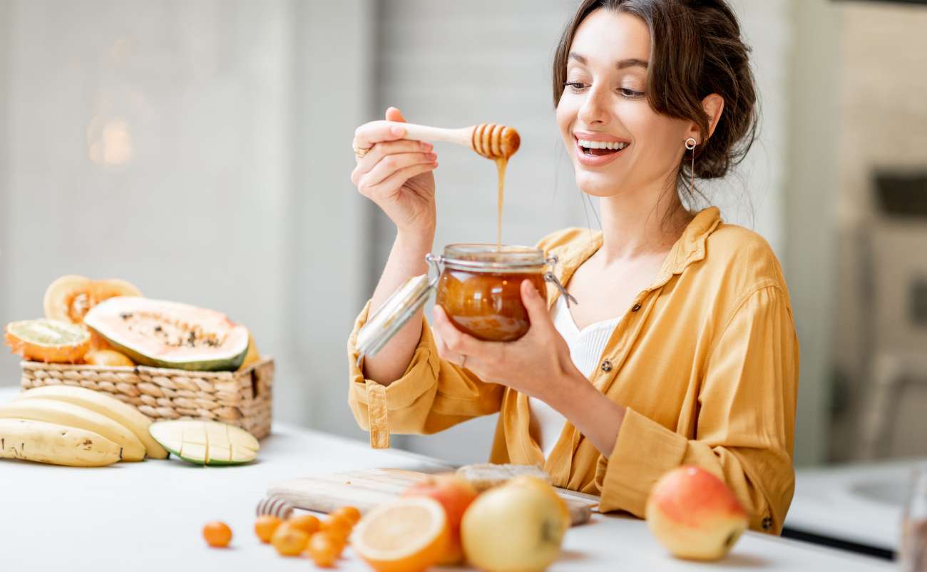 Women quitting sugar and trying honey with fruits in the kitchen