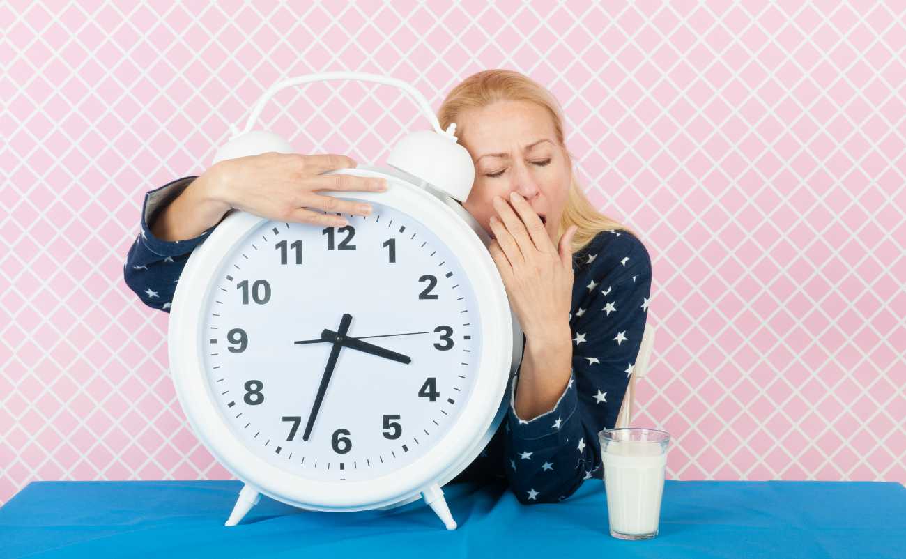 women yawning with big clock looking for insomnia cure