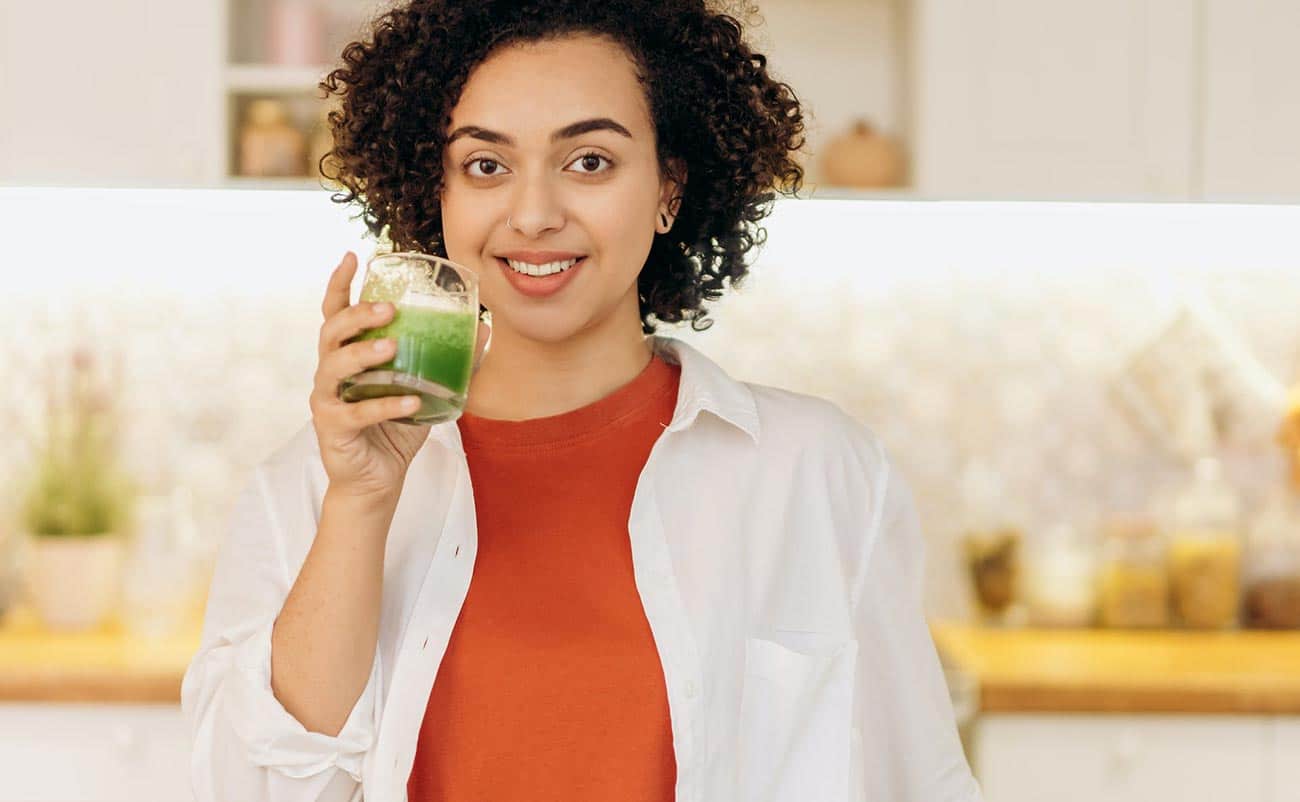 young girl drinking mix vegetable juice in kitchen